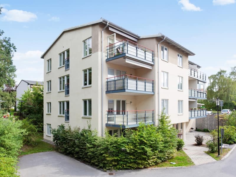 Entrésidan med balkong mot grönområde omgivning